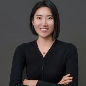 A headshot of Jihyeong Jeong smiling. She is a Korean woman with chin-length black hair and is wearing a black v-neck long-sleeve top.