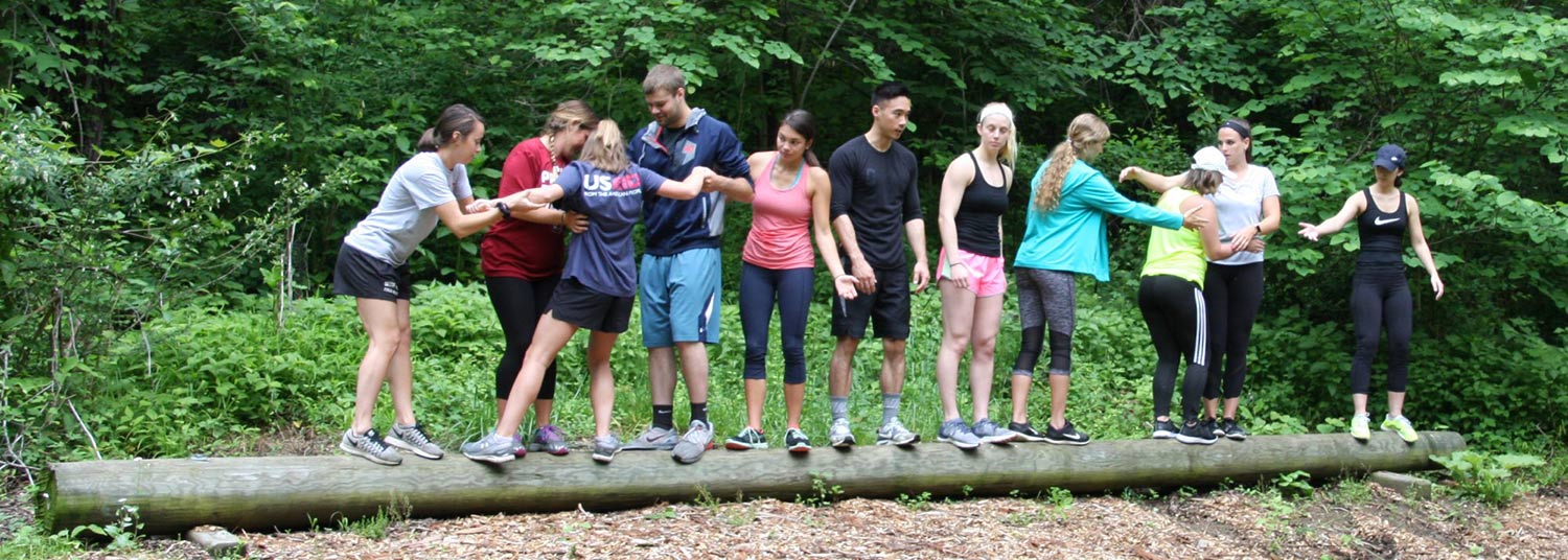 A group of people in the forest standing on a log